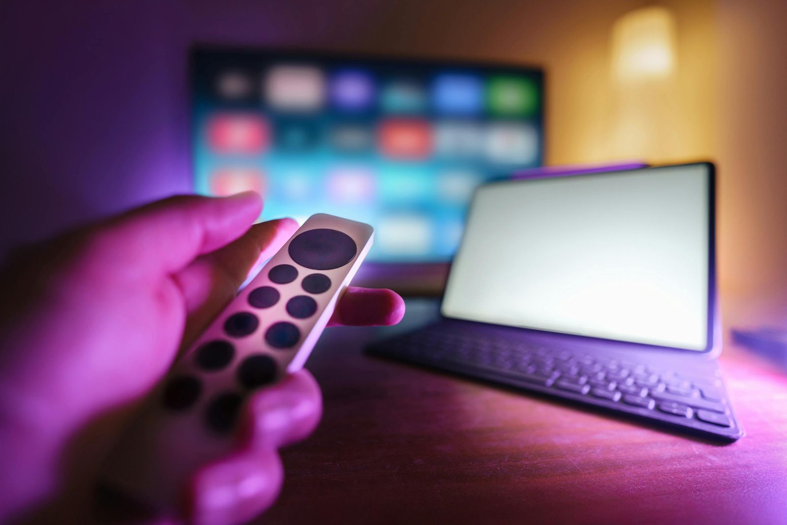 A hand holding a remote in front of a smart TV streaming menu